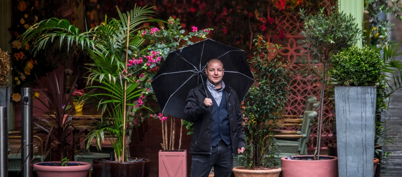 person in suit with umbrella and flowers