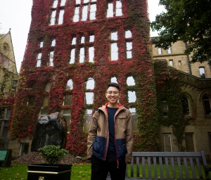  smiling person in front of vine covered wall